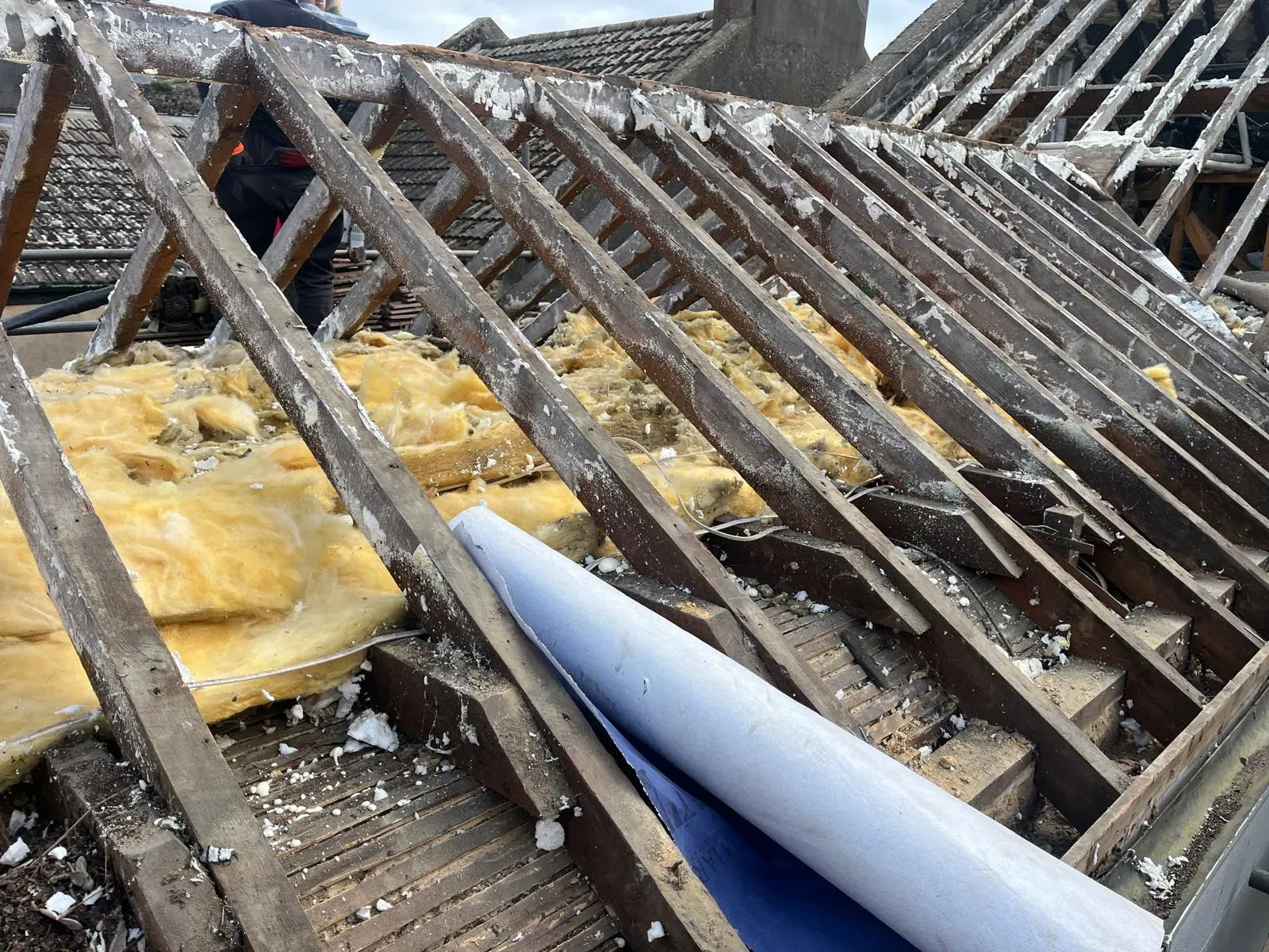 Professional roof replacement and rafter inspection in West Malling, Kent, showing insulation and roofing membrane.