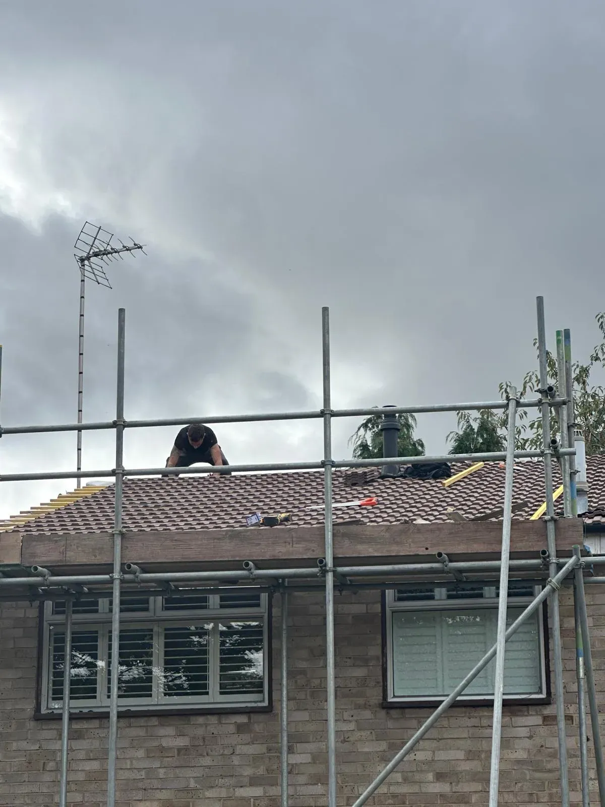 Professional roofer installing a new tiled roof with scaffolding in West Malling, Kent.