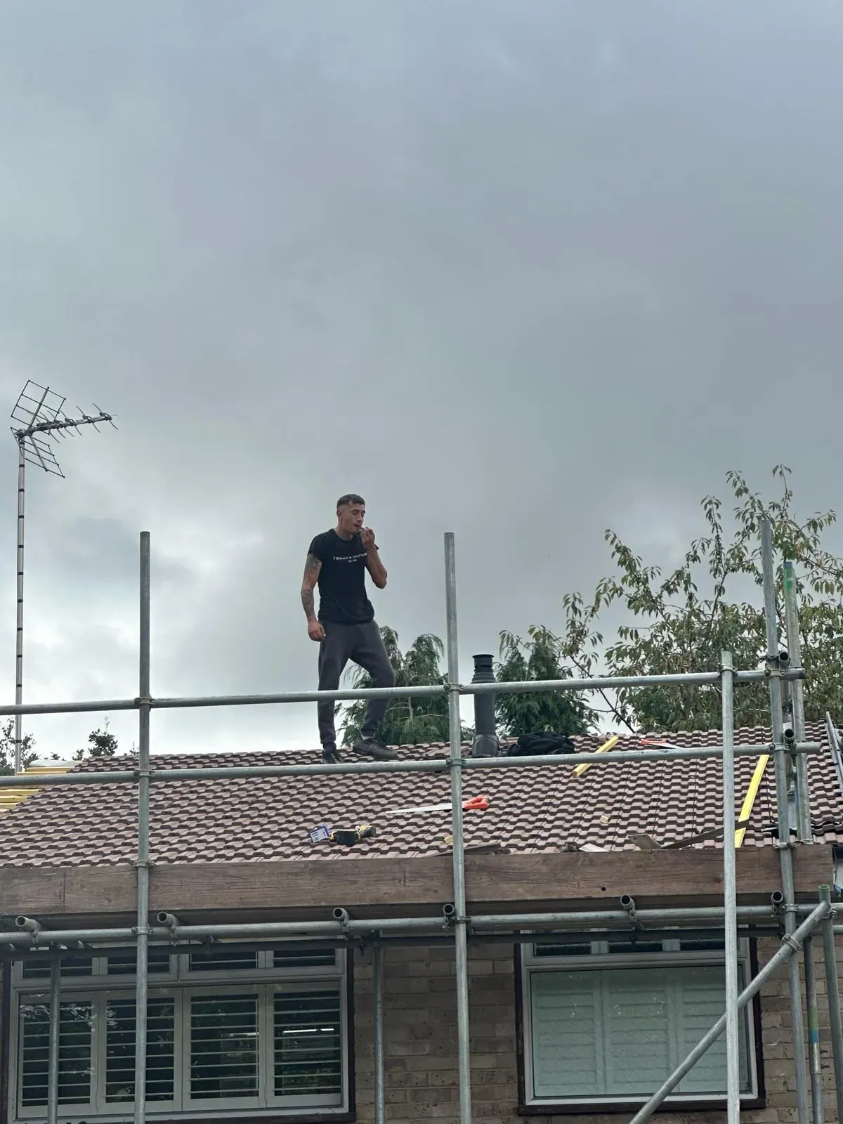 Professional roofer performing a tiled roof replacement in West Malling, Kent, with scaffolding included.